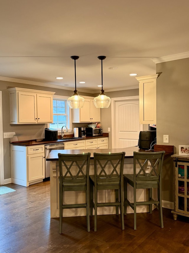 kitchen with dark countertops, a breakfast bar, white cabinets, and pendant lighting