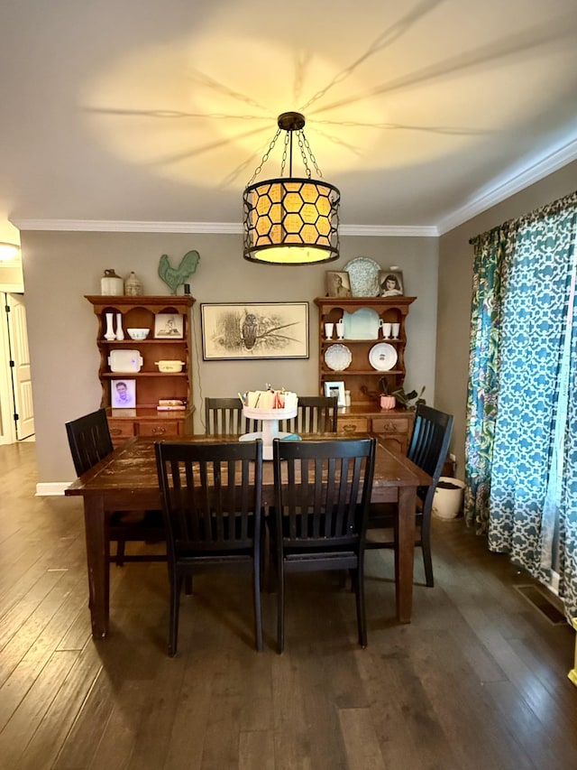 dining area featuring dark wood-type flooring and crown molding