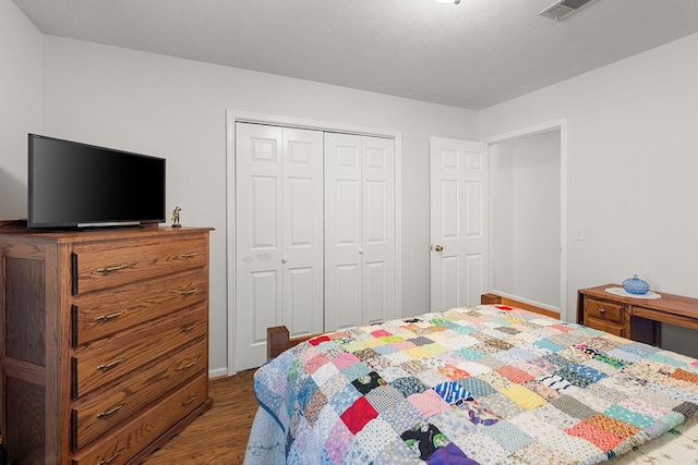 bedroom featuring a closet, wood finished floors, and visible vents