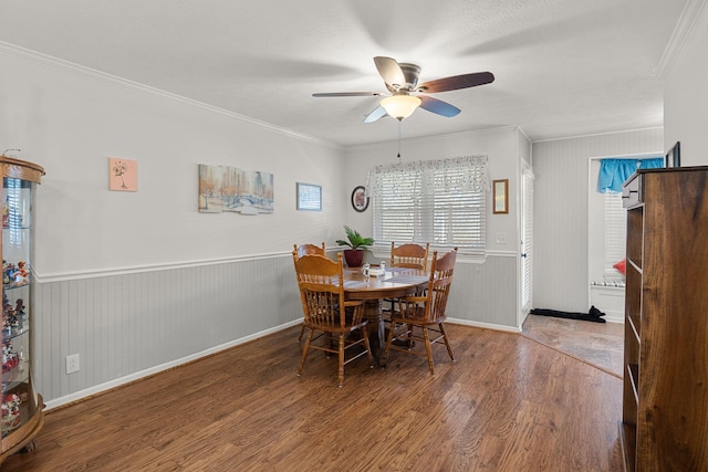 dining room featuring a wainscoted wall, crown molding, ceiling fan, and wood finished floors