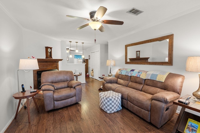 living area featuring dark wood-type flooring, a fireplace, a ceiling fan, visible vents, and crown molding