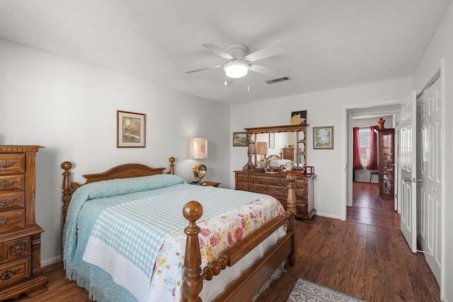 bedroom with a closet, visible vents, dark wood finished floors, and baseboards