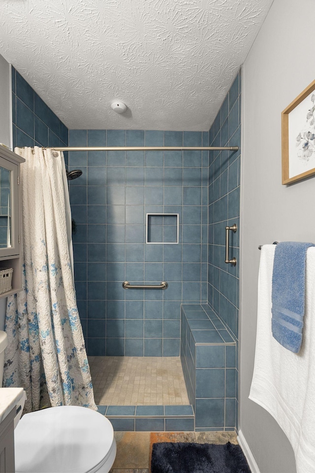 full bathroom featuring toilet, a stall shower, vanity, a textured ceiling, and baseboards