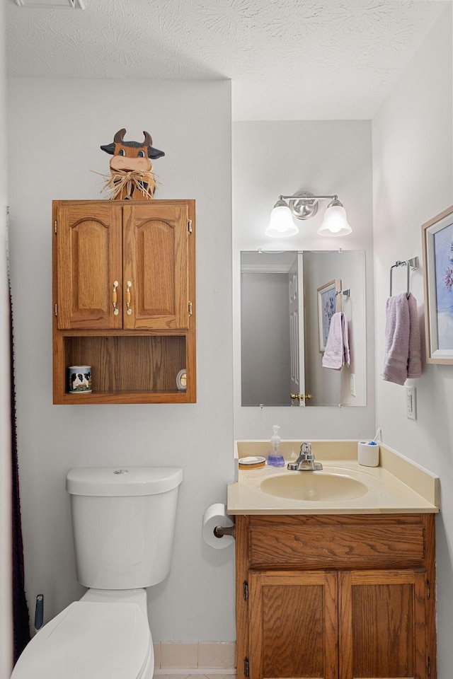 half bathroom featuring toilet, a textured ceiling, and vanity