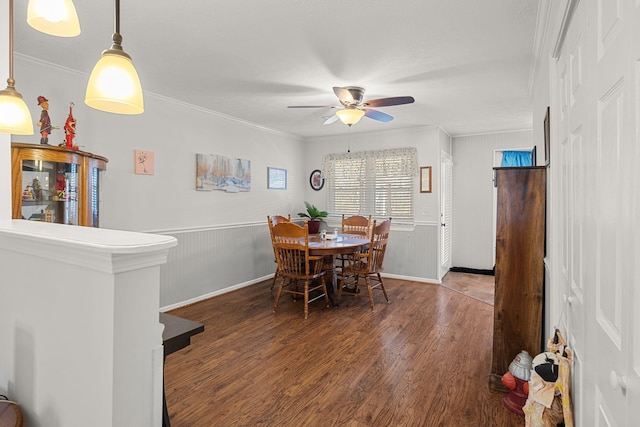 dining area featuring ceiling fan, a wainscoted wall, crown molding, and wood finished floors