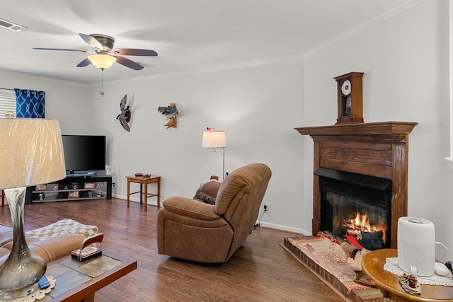 living area with visible vents, dark wood finished floors, crown molding, and a glass covered fireplace