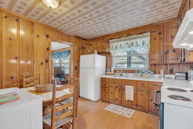 kitchen with brown cabinets, white appliances, light countertops, and ventilation hood