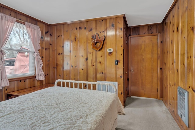 bedroom featuring heating unit, wood walls, and light colored carpet