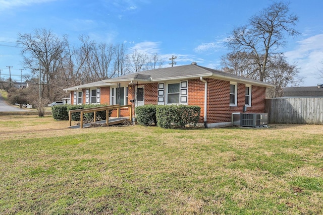 view of front of house with brick siding, a front lawn, central AC unit, and fence