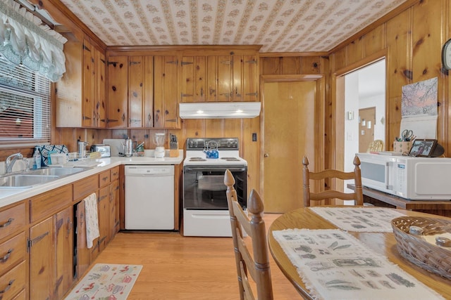 kitchen featuring white appliances, brown cabinets, light countertops, light wood-type flooring, and under cabinet range hood