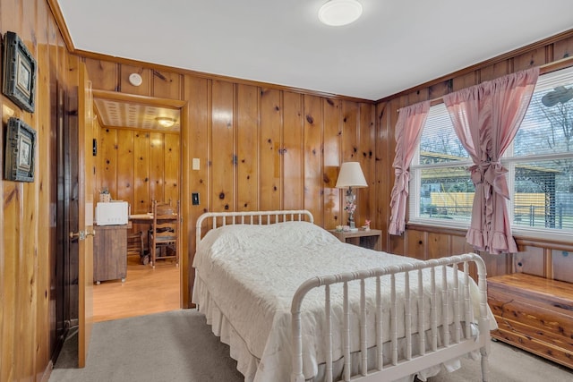 bedroom featuring light carpet and wooden walls