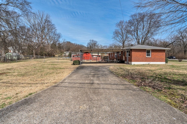 ranch-style home featuring driveway, fence, a front lawn, and brick siding