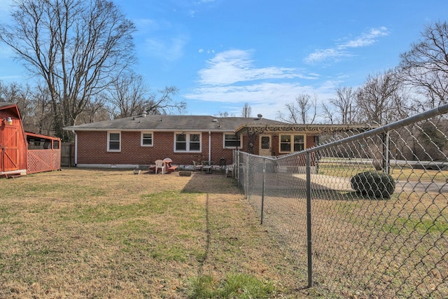 back of house featuring fence, a lawn, and brick siding