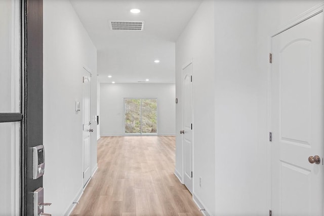 hall featuring light wood-type flooring, visible vents, baseboards, and recessed lighting