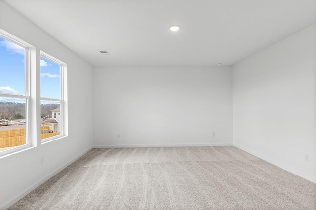 empty room with recessed lighting, baseboards, visible vents, and light colored carpet