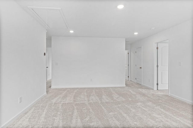 empty room with light carpet, attic access, baseboards, and recessed lighting