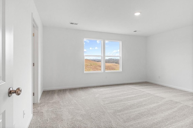 empty room featuring recessed lighting, light colored carpet, visible vents, and baseboards