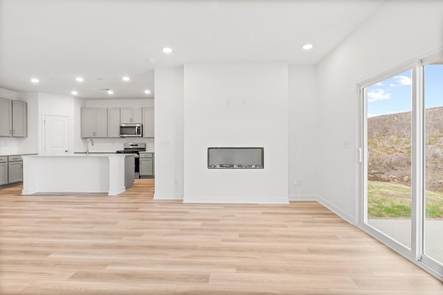 unfurnished living room featuring recessed lighting, a sink, and light wood-style flooring