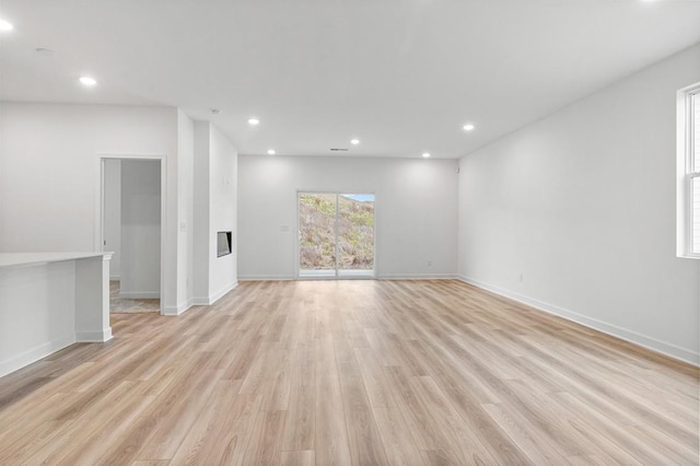 spare room with baseboards, light wood-style floors, and recessed lighting