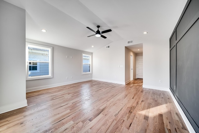 unfurnished living room featuring lofted ceiling, a ceiling fan, baseboards, visible vents, and light wood-style floors