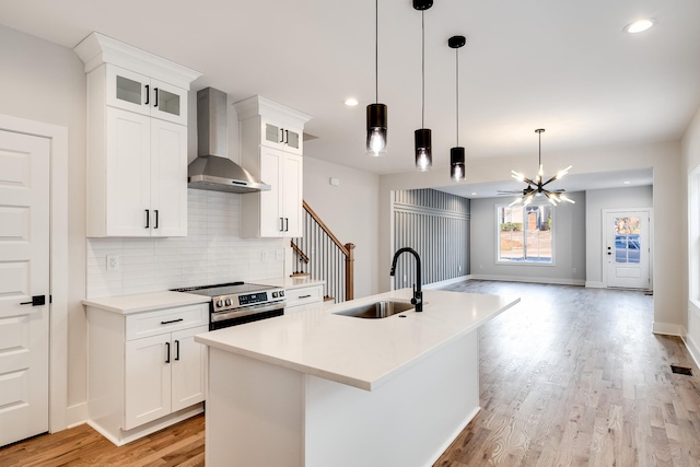 kitchen with wall chimney exhaust hood, a sink, stainless steel electric stove, light wood-style floors, and backsplash