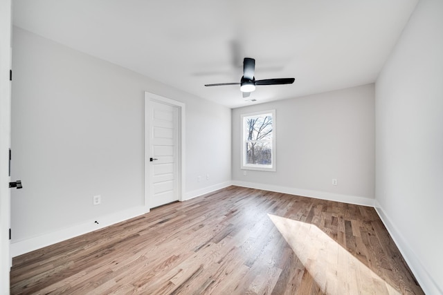 empty room with wood finished floors, a ceiling fan, and baseboards