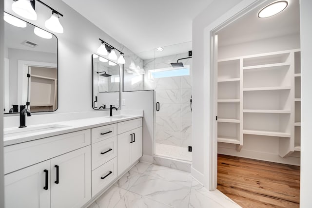 bathroom featuring marble finish floor, a sink, a marble finish shower, and double vanity