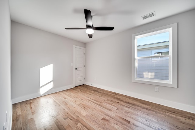 empty room with ceiling fan, wood finished floors, visible vents, and baseboards