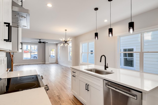 kitchen featuring stainless steel appliances, a sink, open floor plan, light wood finished floors, and pendant lighting