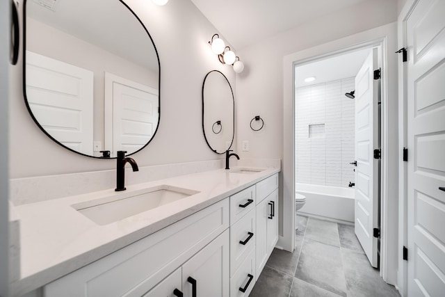 bathroom featuring double vanity, toilet, tub / shower combination, and a sink