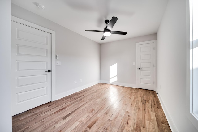 spare room featuring ceiling fan, light wood-style flooring, and baseboards