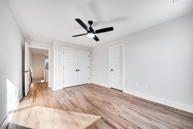 unfurnished bedroom featuring light wood-style floors, a closet, ceiling fan, and baseboards