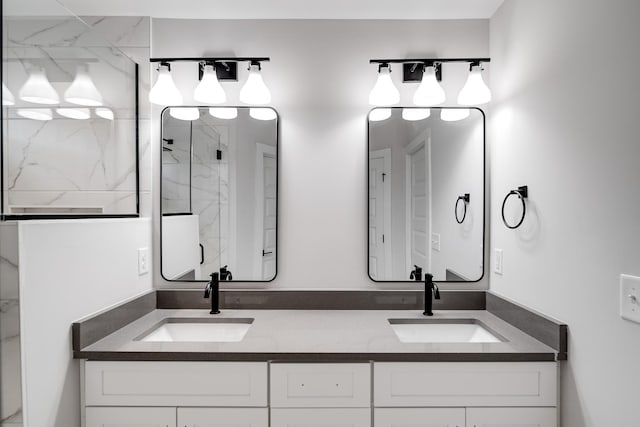 bathroom featuring double vanity, a marble finish shower, and a sink