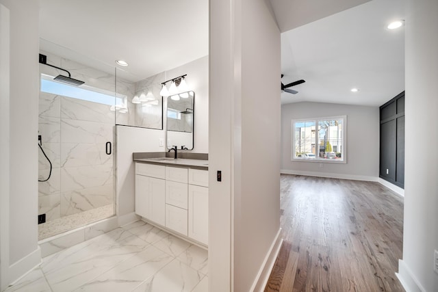 full bath featuring lofted ceiling, vanity, baseboards, marble finish floor, and a marble finish shower