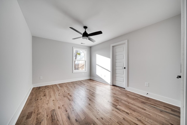 spare room featuring a ceiling fan, visible vents, baseboards, and wood finished floors