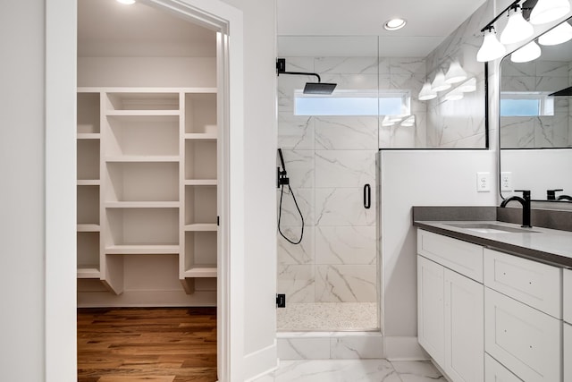 full bathroom featuring recessed lighting, vanity, marble finish floor, a marble finish shower, and a walk in closet