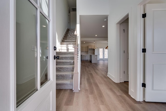 foyer entrance with light wood-style floors, baseboards, stairway, and recessed lighting