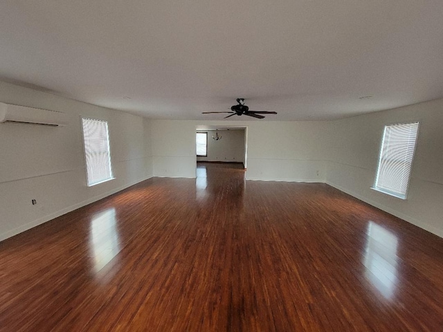 empty room with dark wood-style floors, an AC wall unit, and ceiling fan