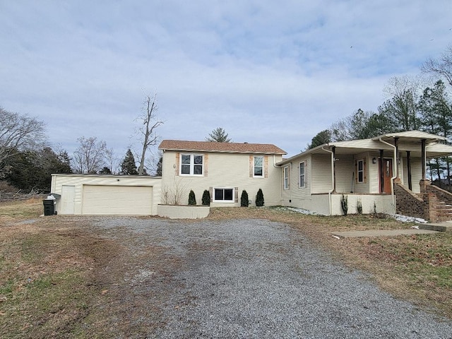 view of front of home featuring a garage, covered porch, and gravel driveway