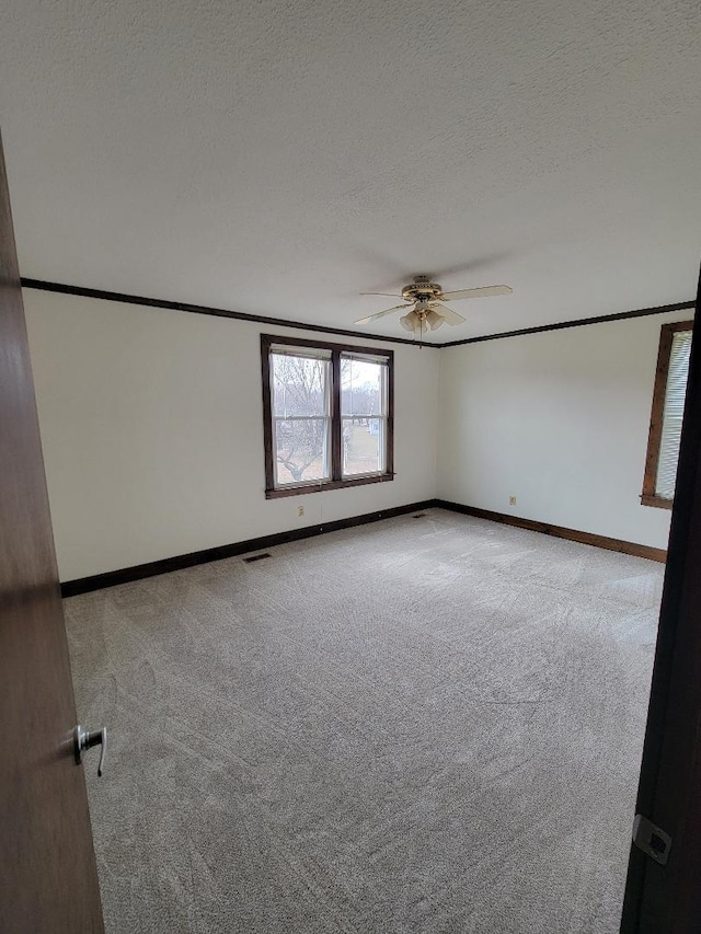 spare room featuring light colored carpet, ceiling fan, a textured ceiling, and baseboards