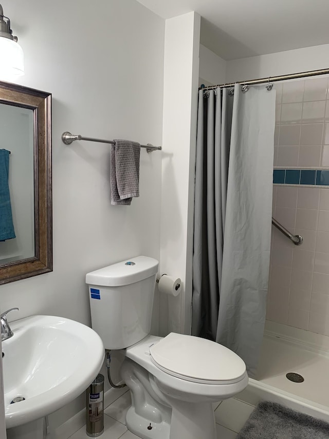 bathroom with tile patterned flooring, a sink, a shower stall, and toilet