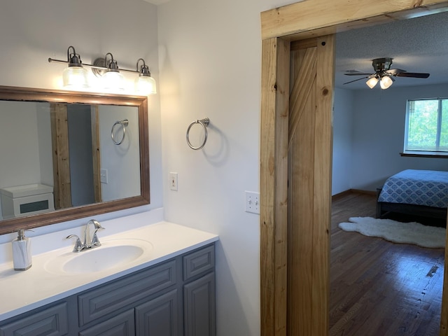 ensuite bathroom with ceiling fan, ensuite bathroom, wood finished floors, and vanity