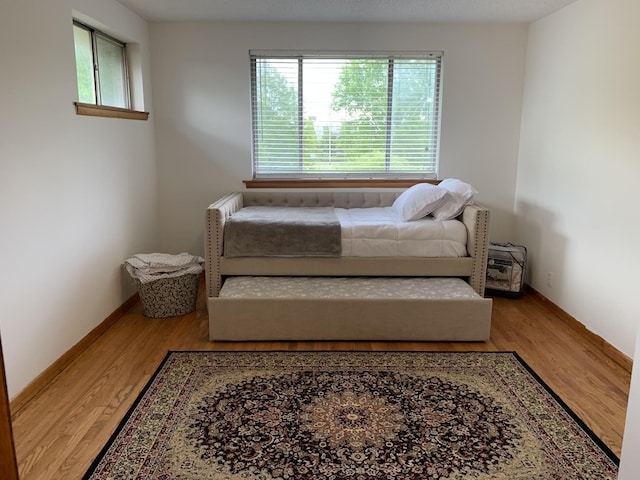 bedroom with multiple windows, baseboards, and wood finished floors