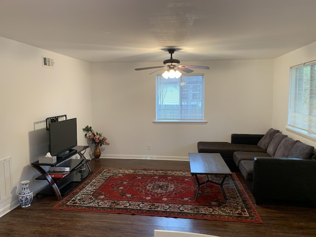 living room featuring ceiling fan, baseboards, visible vents, and dark wood finished floors