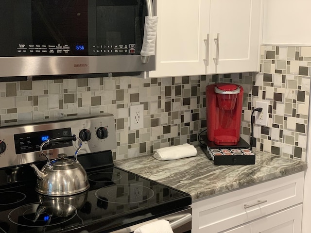 kitchen featuring stainless steel appliances, white cabinetry, and light stone counters