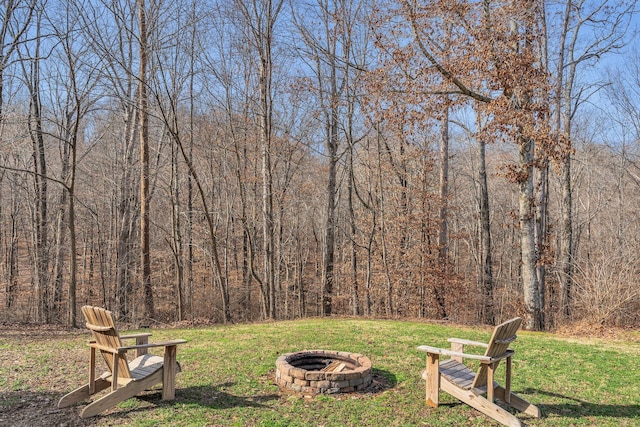 view of yard with a fire pit and a view of trees