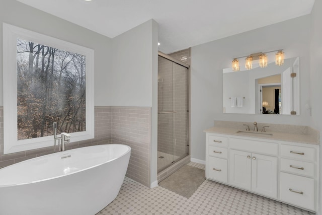 full bathroom featuring tile walls, a freestanding tub, a shower stall, and vanity