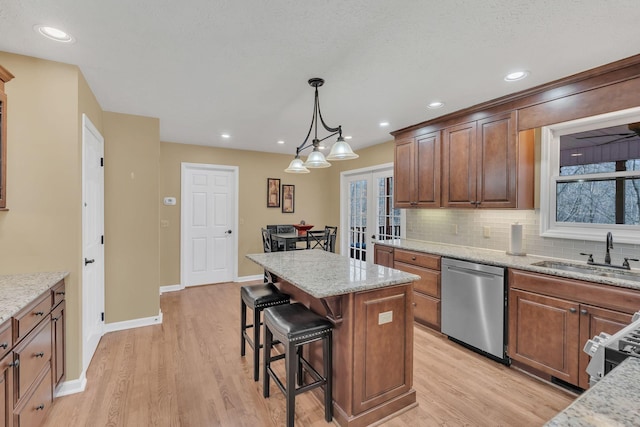 kitchen featuring a sink, light stone countertops, a kitchen island, and dishwasher