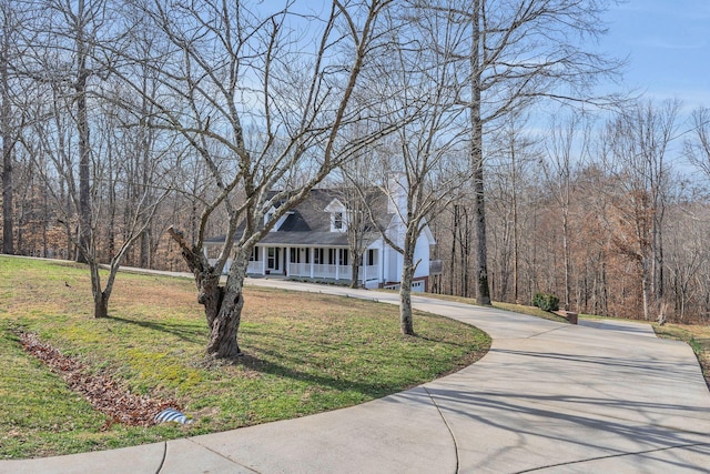 new england style home featuring a porch, driveway, and a front lawn