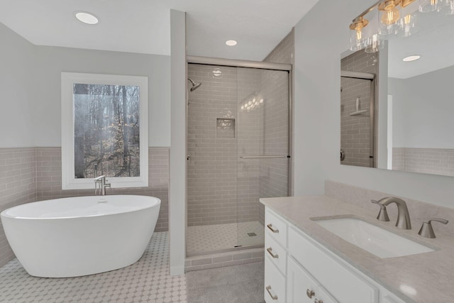 full bathroom featuring tile walls, a soaking tub, vanity, and a shower stall